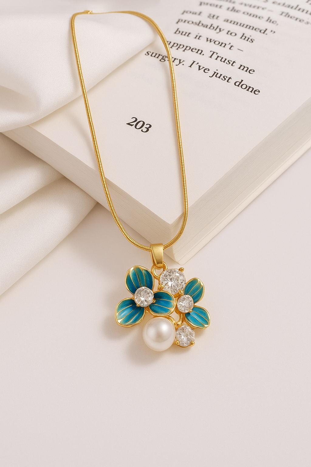 elira-bloom-pendant.jpg Elira Bloom Pendant in gold with three enamel blue petals, sparkling diamond accents, and a central pearl. Anti tarnish, elegant floral necklace for daily wear.